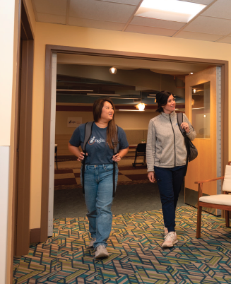 Two women with Inglis Assistive Tech, walk down a hallway