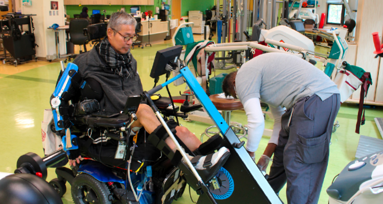 Resident on the new Physical Therapy Bike, being assisted by a Physical Therapy Assistant